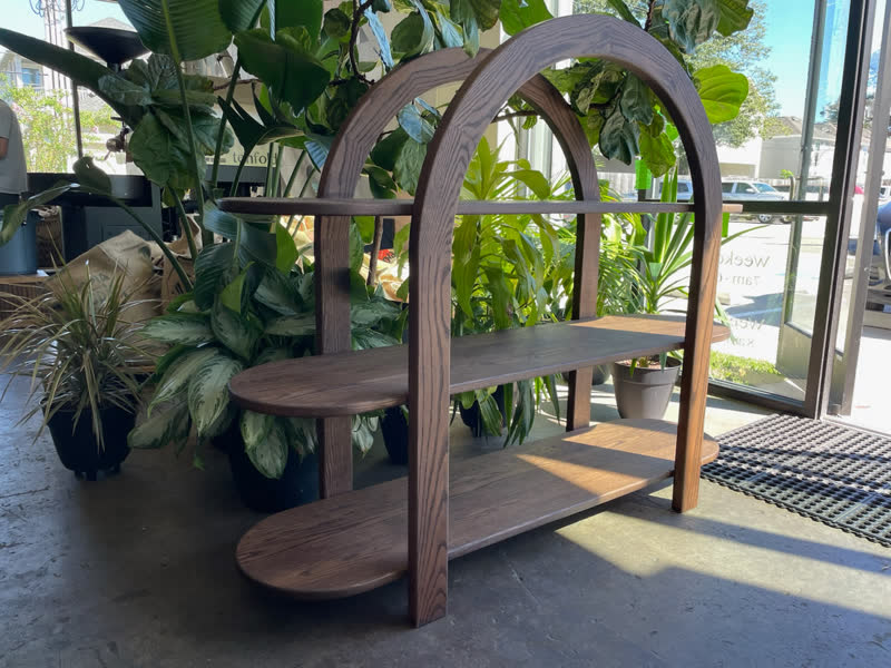 An arched oak display shelf built for a coffee shop, surrounded by plants