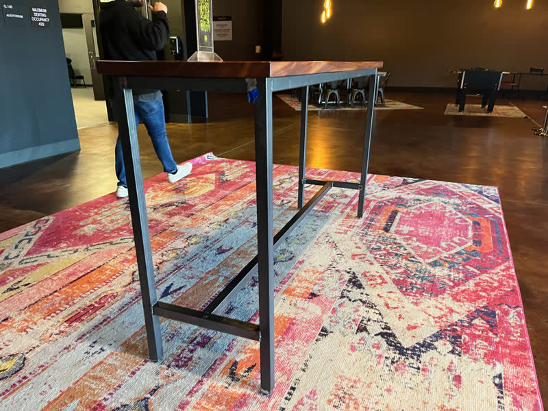 A bar-height table with a walnut top and steel legs, installed in a client's lobby