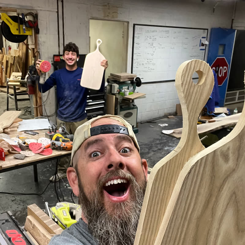 A mentor and a student celebrating a fresh batch of cutting boards