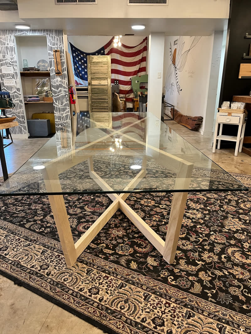 The glass-top table with its light ash base, shown on the shop floor