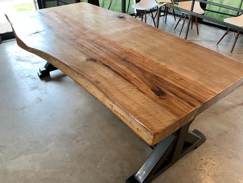 A finished live-edge dining table with a steel trestle base