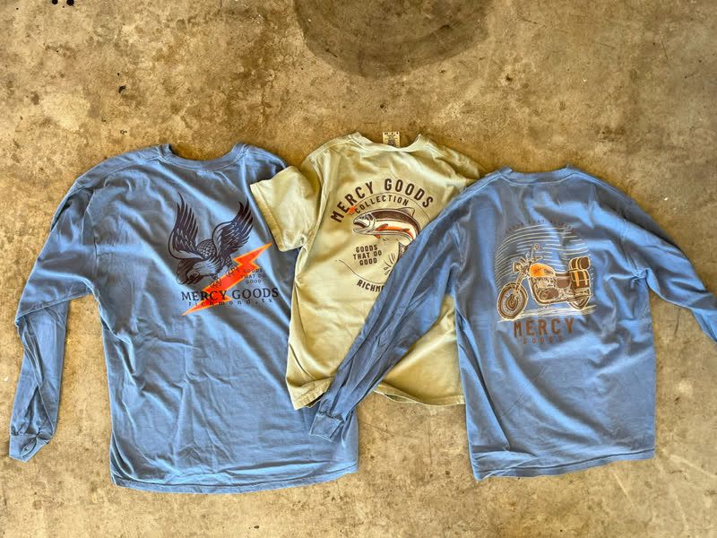 Mercy Goods merchandise shirts laid out in the shop