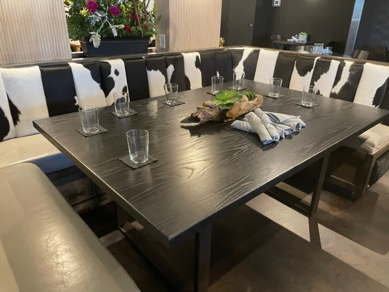A dark-stained square table set in a restaurant with cowhide booth seating