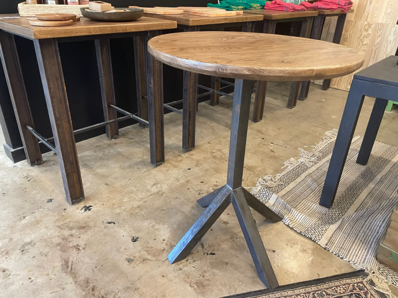 A round pedestal café table with a black steel tripod base in the shop