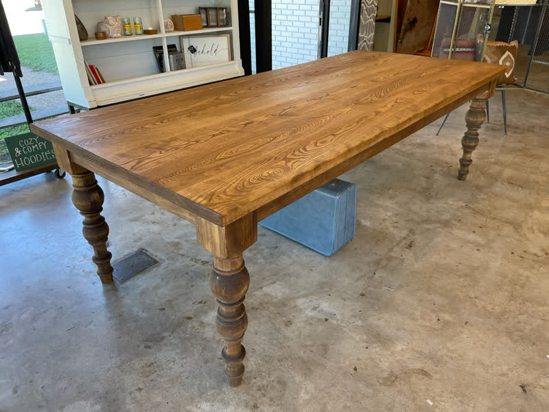 A long dining table with hand-turned wooden legs in the Mercy Goods shop