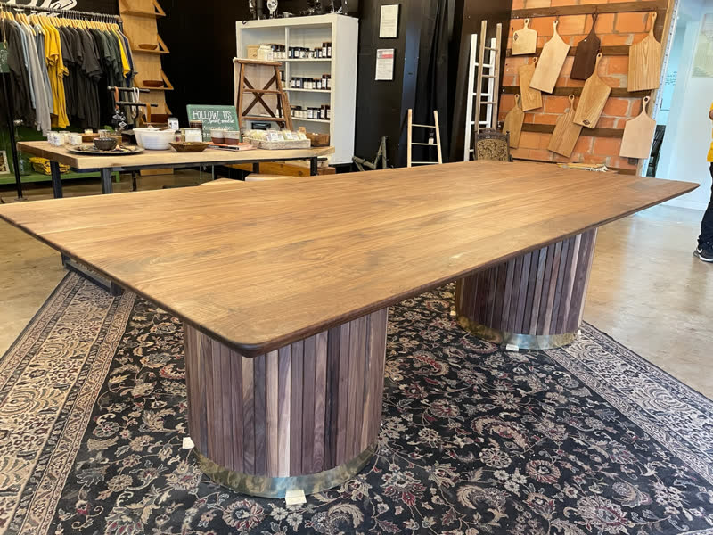 A large walnut dining table with fluted drum pedestals in the Mercy Goods shop