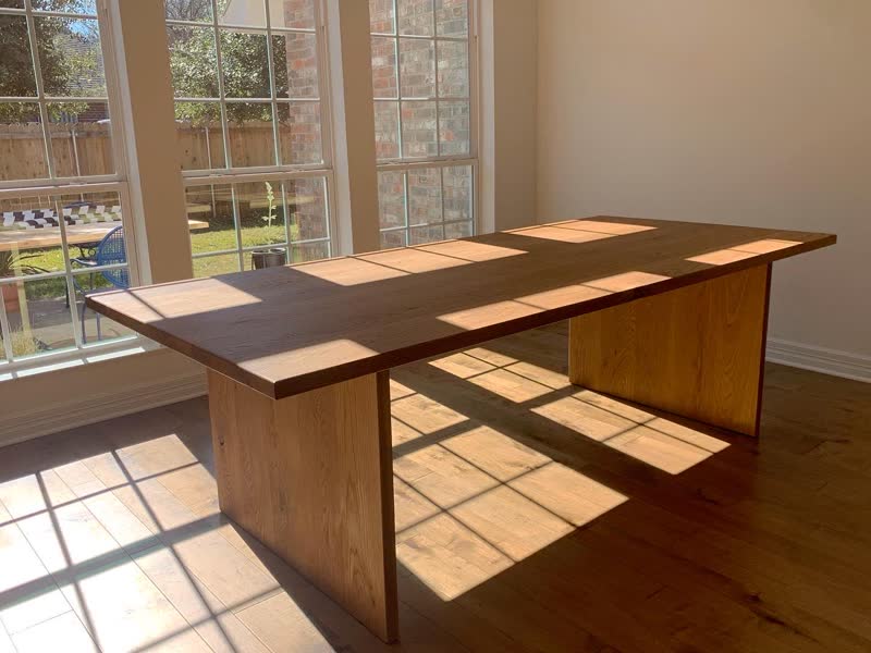 A walnut waterfall dining table in a sunlit client dining room